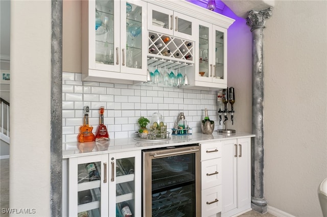 bar with wine cooler, white cabinetry, and decorative backsplash