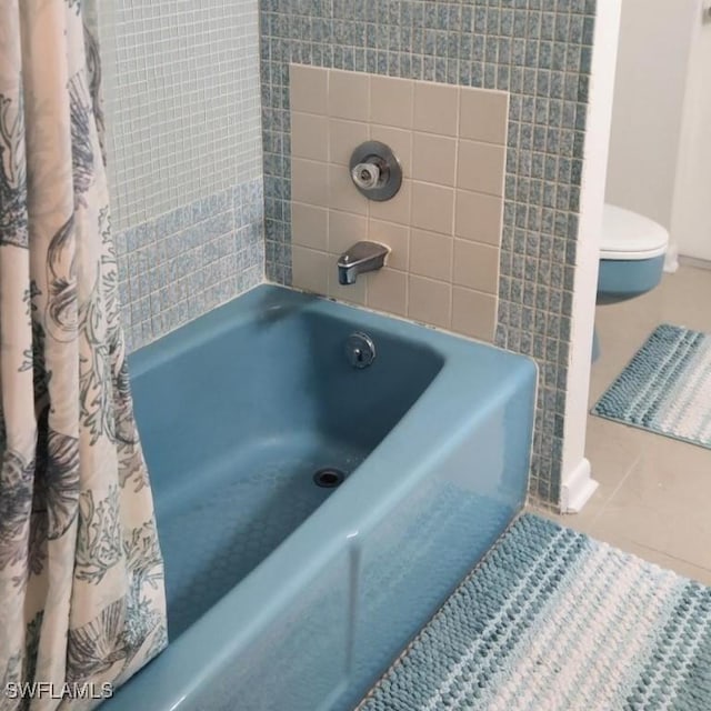 bathroom with tile patterned floors, shower / tub combo, and toilet