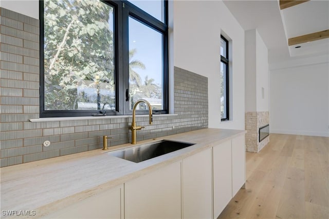 kitchen with decorative backsplash, sink, light hardwood / wood-style flooring, and white cabinets