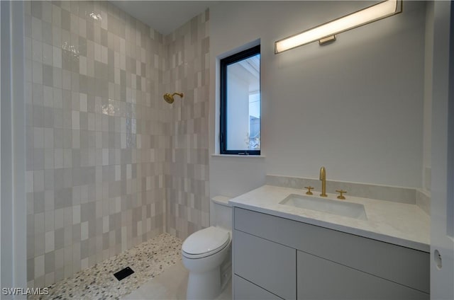 bathroom with vanity, toilet, and tiled shower