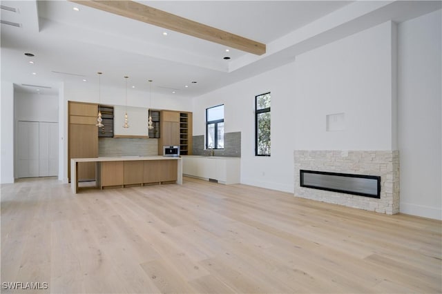 unfurnished living room featuring light hardwood / wood-style flooring, a fireplace, and beamed ceiling