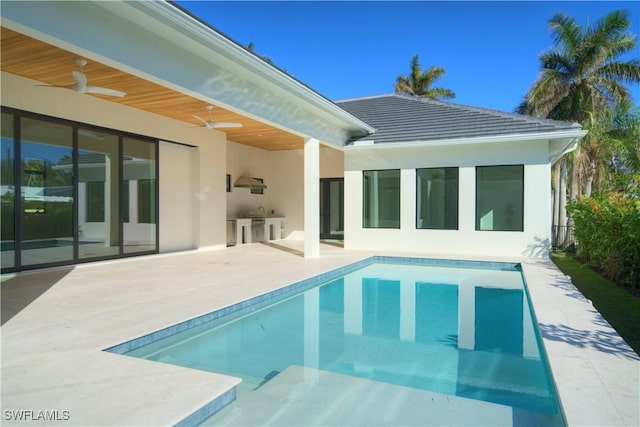 view of pool with an outdoor kitchen, ceiling fan, and a patio