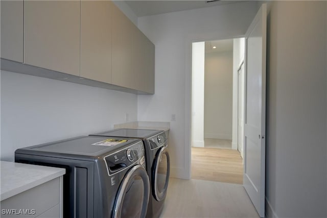 laundry area featuring cabinets, washer and dryer, and light hardwood / wood-style floors