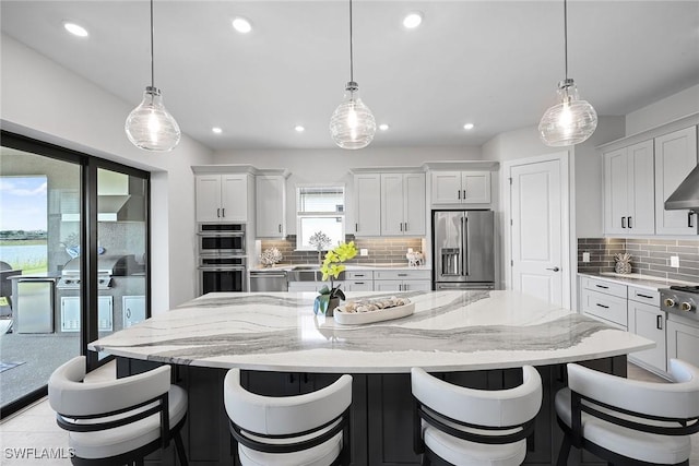 kitchen with a large island, white cabinetry, stainless steel appliances, and hanging light fixtures