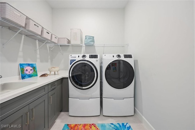 laundry area featuring washer and clothes dryer, light tile patterned flooring, cabinets, and sink