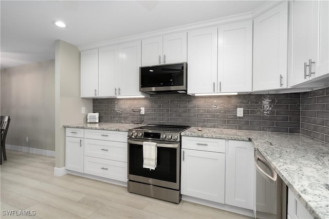 kitchen with light wood-type flooring, tasteful backsplash, light stone counters, white cabinetry, and stainless steel appliances