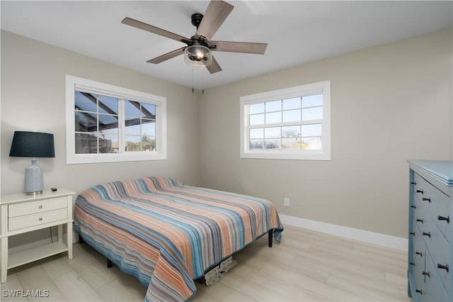 bedroom featuring ceiling fan, light wood-type flooring, and multiple windows