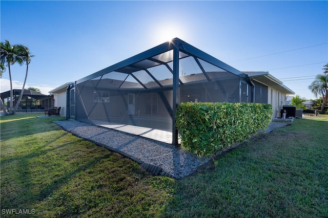 view of side of home with a lawn and glass enclosure