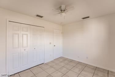 unfurnished bedroom with ceiling fan, light tile patterned flooring, and a closet