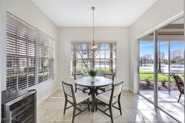 dining room featuring light tile patterned floors, a water view, an inviting chandelier, and beverage cooler