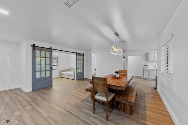 dining area featuring a barn door and light hardwood / wood-style floors