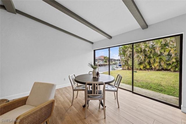 dining area featuring a water view, beam ceiling, and light hardwood / wood-style flooring