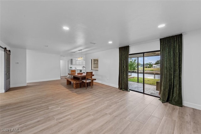 unfurnished dining area featuring a barn door and light wood-type flooring