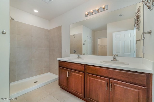 bathroom with tile patterned flooring, vanity, and a tile shower