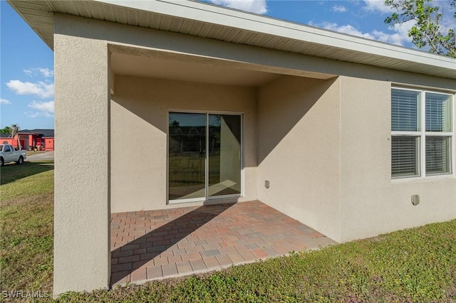 property entrance with a lawn and a patio