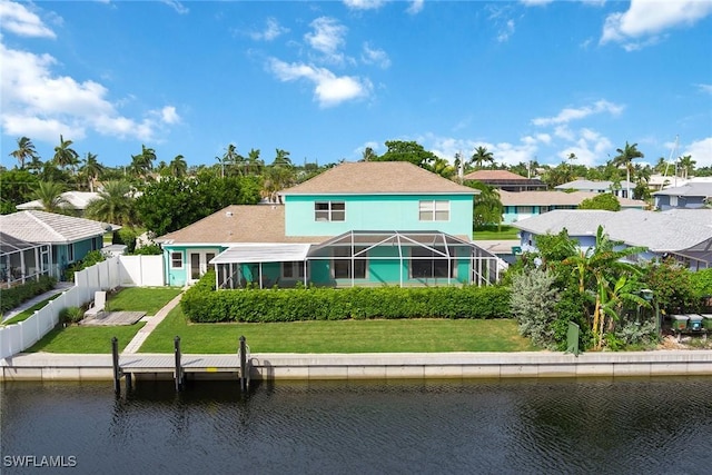 rear view of property featuring glass enclosure, a water view, and a yard