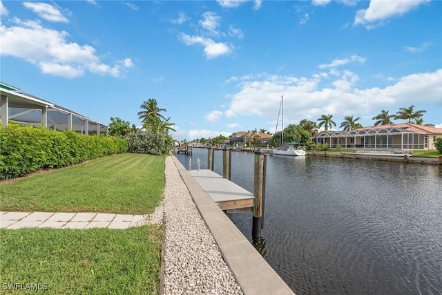 dock area with a lawn, glass enclosure, and a water view