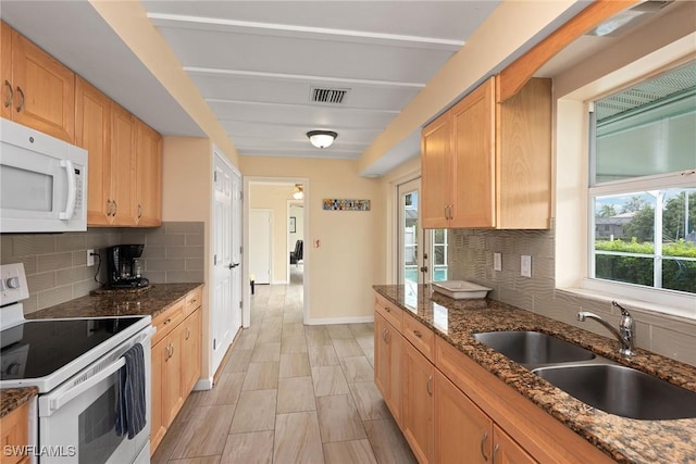 kitchen with dark stone countertops, sink, a healthy amount of sunlight, and white appliances