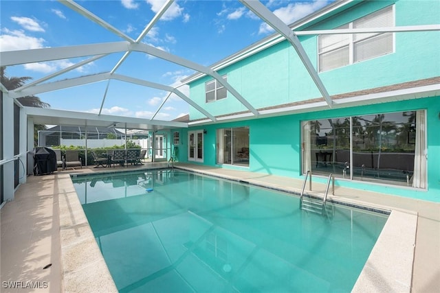 view of swimming pool with glass enclosure, a grill, and a patio area