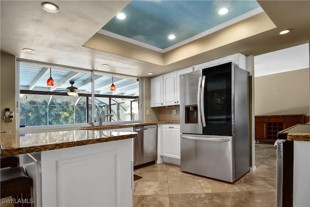 kitchen with a tray ceiling, white cabinetry, ceiling fan, and appliances with stainless steel finishes