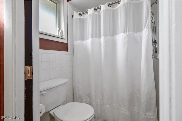 bathroom featuring toilet and tile walls