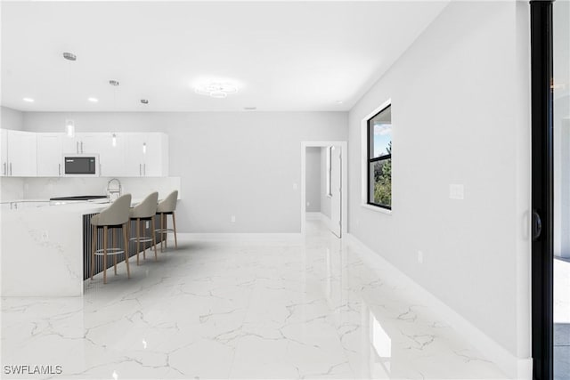 interior space featuring pendant lighting, white cabinetry, a kitchen breakfast bar, and black microwave