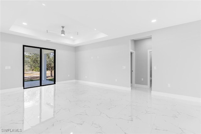 spare room featuring ceiling fan and a raised ceiling