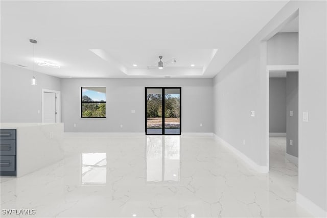 unfurnished living room with ceiling fan and a raised ceiling