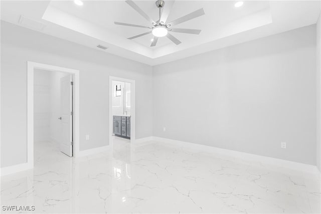 spare room with a tray ceiling and ceiling fan