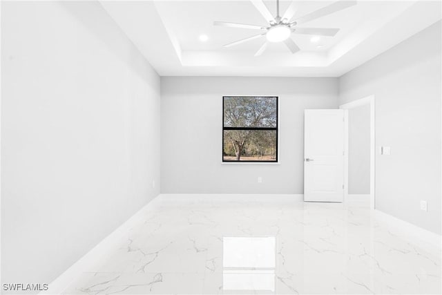 unfurnished room featuring a raised ceiling and ceiling fan