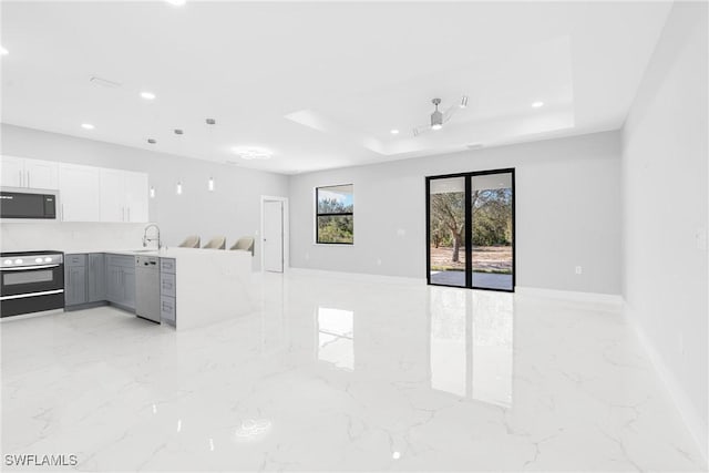 unfurnished living room with a tray ceiling and ceiling fan