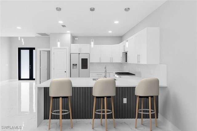 kitchen featuring white refrigerator with ice dispenser, white cabinets, kitchen peninsula, and a breakfast bar area