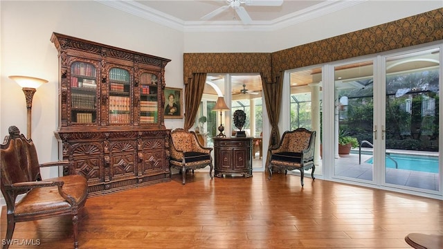 living area with ceiling fan, light hardwood / wood-style floors, and ornamental molding