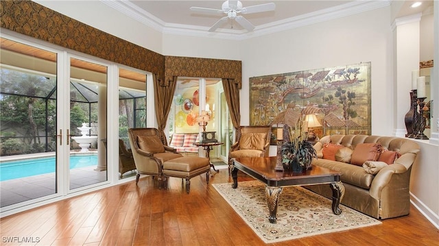 living area featuring wood-type flooring, ceiling fan, and crown molding