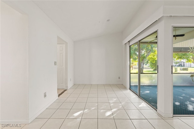 empty room with light tile patterned floors and vaulted ceiling