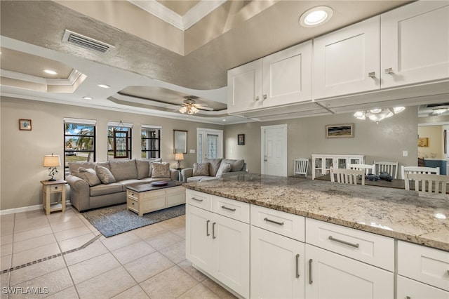 kitchen featuring a tray ceiling, ceiling fan, white cabinetry, and light stone countertops