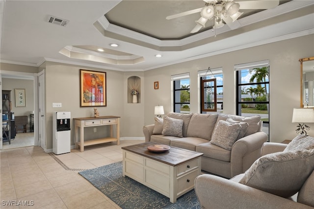 tiled living room with a tray ceiling, ceiling fan, and ornamental molding