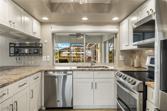 kitchen with decorative backsplash, appliances with stainless steel finishes, light stone countertops, sink, and white cabinets