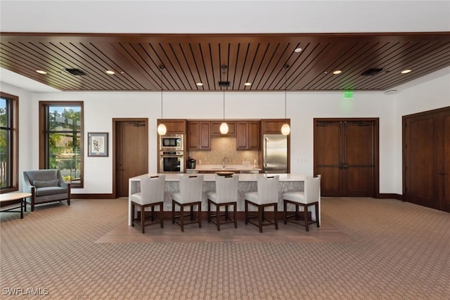 kitchen featuring pendant lighting, a breakfast bar, dark carpet, backsplash, and stainless steel appliances