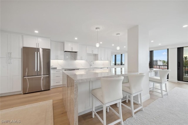 kitchen with white cabinetry, sink, light hardwood / wood-style floors, decorative light fixtures, and appliances with stainless steel finishes