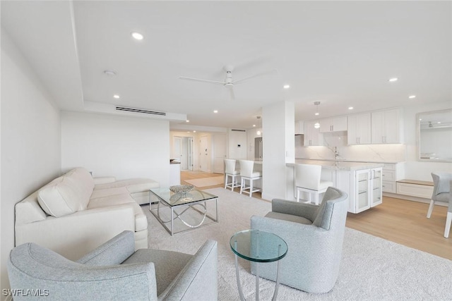 living room with ceiling fan, sink, and light hardwood / wood-style floors