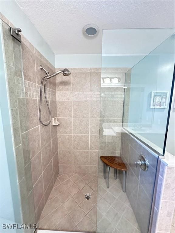 bathroom featuring a tile shower, tile patterned floors, and a textured ceiling