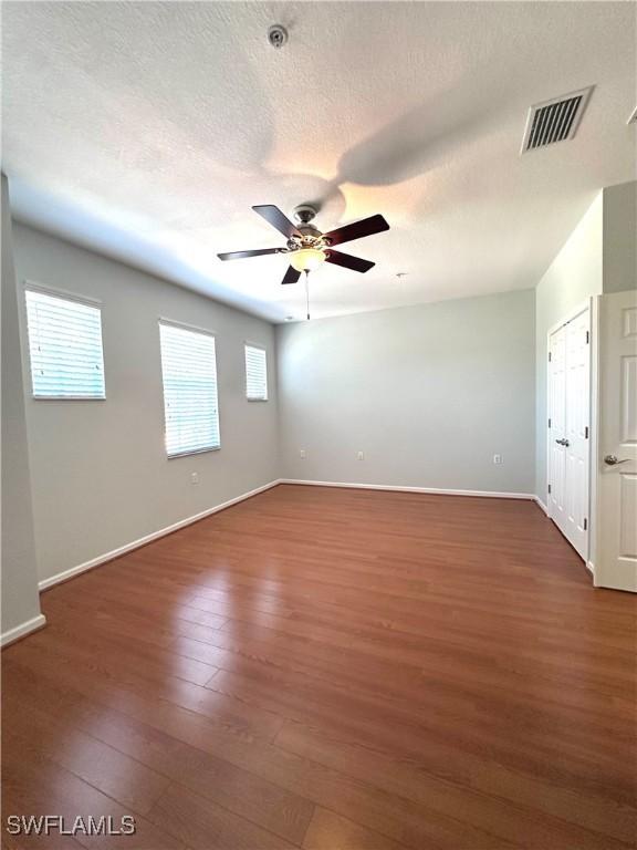 unfurnished room with a textured ceiling, ceiling fan, and dark wood-type flooring