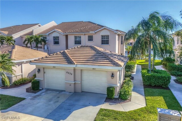 view of property featuring driveway, stucco siding, and a tiled roof