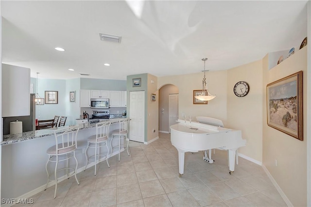 dining area with arched walkways, light tile patterned floors, recessed lighting, visible vents, and baseboards