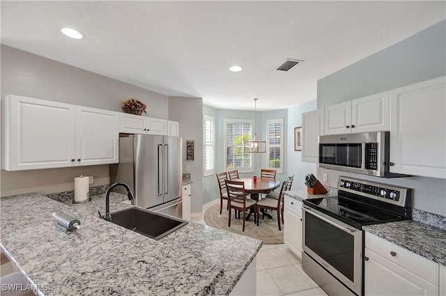 kitchen with stainless steel appliances, visible vents, white cabinets, a sink, and a peninsula