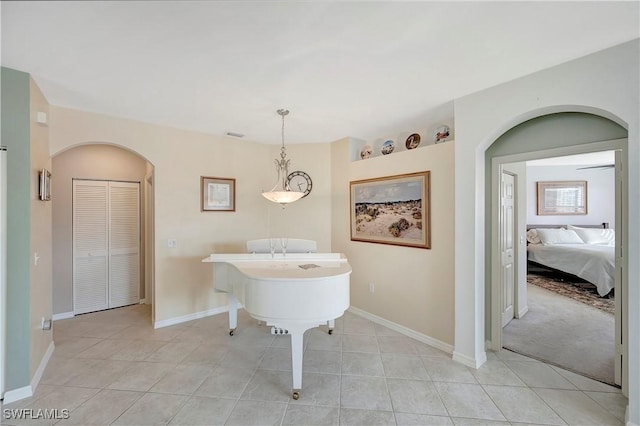 dining area with arched walkways, light tile patterned floors, and baseboards