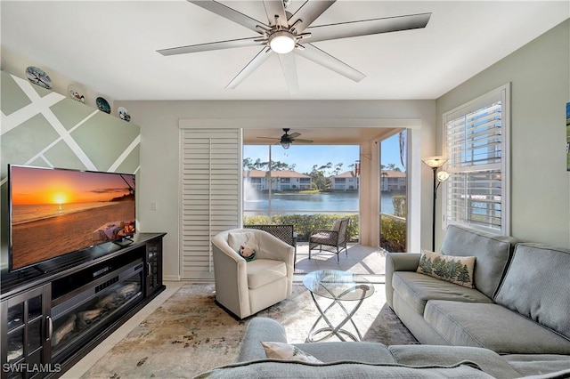 living area featuring plenty of natural light, a ceiling fan, and a water view