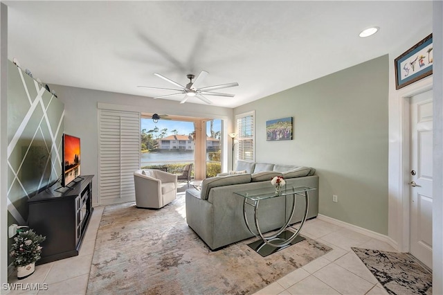 living room featuring light tile patterned floors, a ceiling fan, and baseboards