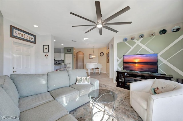 living room featuring arched walkways, a ceiling fan, and recessed lighting